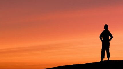 Obraz premium A silhouette of an empowered mature female stands at the edge of a new life phase. The warm sunrise fills the sky with amber and coral colors.