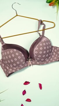 Beige bra with white daisy pattern hanging on hanger lingerie undergarment women female fashion lingerie undergarment women female fashion