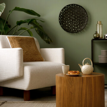 Cozy Living Room Corner with White Armchair, Wooden Table, Tea Set, and Green Wall Decor