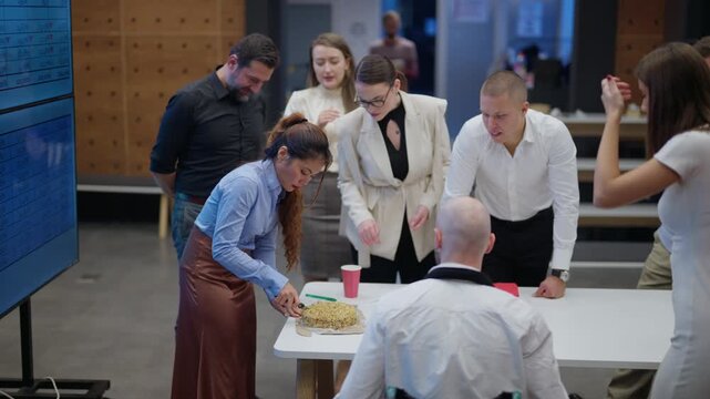 A group of colleagues gathers to celebrate, enjoying a shared moment over cake. Diverse employees joyfully interact during a festive office occasion.
