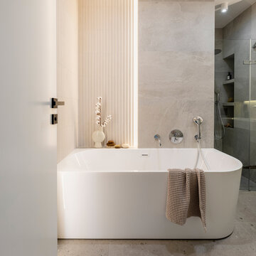 Modern bright bathroom with lamella wall. Big white bath with silver faucet and brown towel.