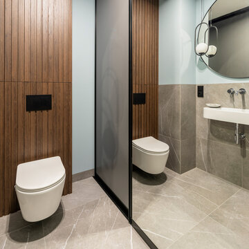 Modern restroom interior with dual toilet stalls, sleek design, wooden panels, and contemporary fixtures for commercial spaces