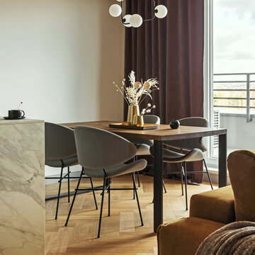 Modern dining area with warm wood table, chairs, and minimalist decor, featuring a stylish chandelier and natural light from a balcony