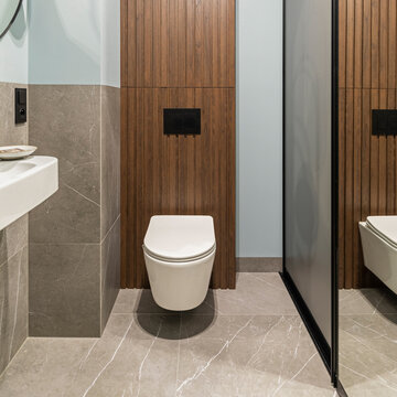Modern light blue and wooden lavatory with a pristine white toilet and elegant gray marble details, contemporary design