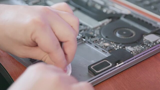 A specialist wipes the inside surface of the laptop case with a white napkin to remove traces of glue and dust.