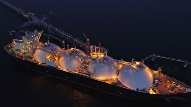 Aerial of Liquified Natural Gas LNG carrier moored to a small gas terminal at night. Fuel crisis. Sanctions