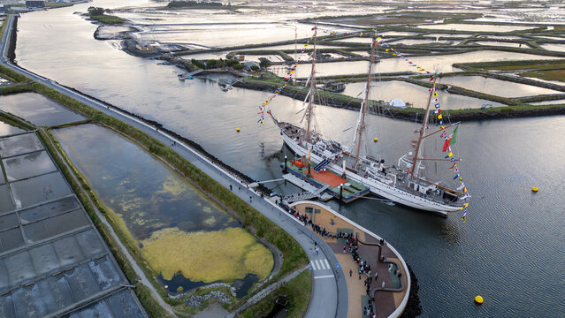 Aerial view of the tall ship NRP Sagres decorated with signal flags navigating the Canal de Aveiro near the salt pans Aveiro, Aveiro, Portugal.