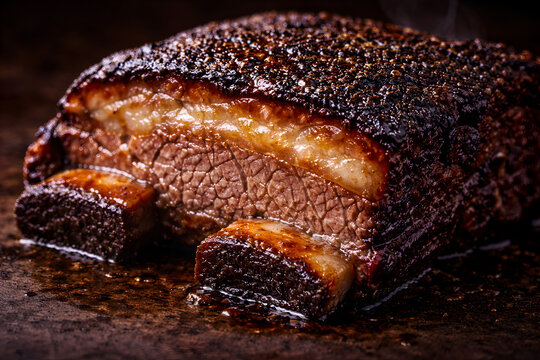 A close-up, high-angle shot of a succulent, slow-smoked beef short rib featuring a dark, seasoned bark, a thick layer of rendered fat, and tender meat.