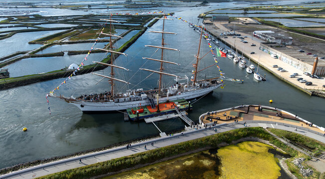Aerial view of the tall ship NRP Sagres decorated with signal flags navigating the Canal de Aveiro near the salt pans Aveiro, Aveiro, Portugal.