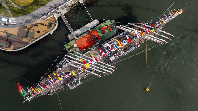Aerial view of the tall ship NRP Sagres decorated with signal flags navigating the Canal de Aveiro near the salt pans Aveiro, Aveiro, Portugal.