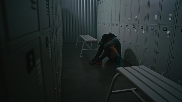 Athletic Woman Sitting on Floor, After Grueling Session. Despite Pain and Exhaustion in Locker Room, Girl Had Inner Strength Continue. Concept of Raw Emotion. Powerful Portrayal of Female Resilience.