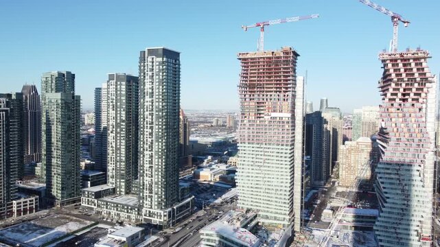 Condominiums under construction, in downtown Mississauga, Canada. Aerial, shot with a drone moving right, on a winter afternoon in December, 2021.
