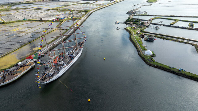 Aerial view of the tall ship NRP Sagres decorated with signal flags navigating the Canal de Aveiro near the salt pans Aveiro, Aveiro, Portugal.