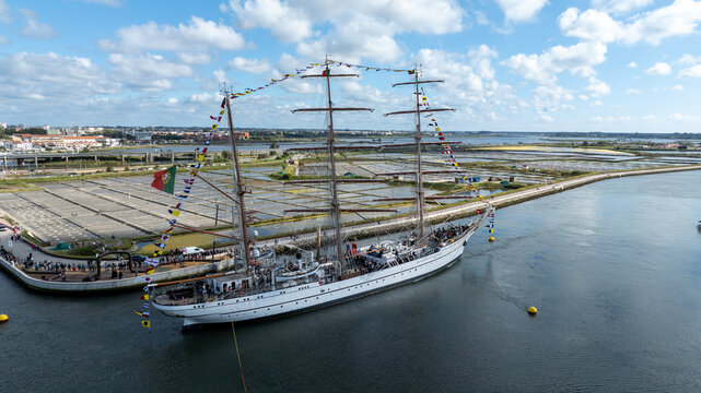 Aerial view of the tall ship NRP Sagres decorated with signal flags navigating the Canal de Aveiro near the salt pans Aveiro, Aveiro, Portugal.
