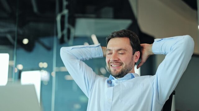 Pleased male manager closing laptop computer and leaning back in office chair with hands behind head. Satisfied corporate employee celebrating project completion and enjoying stress free workday.