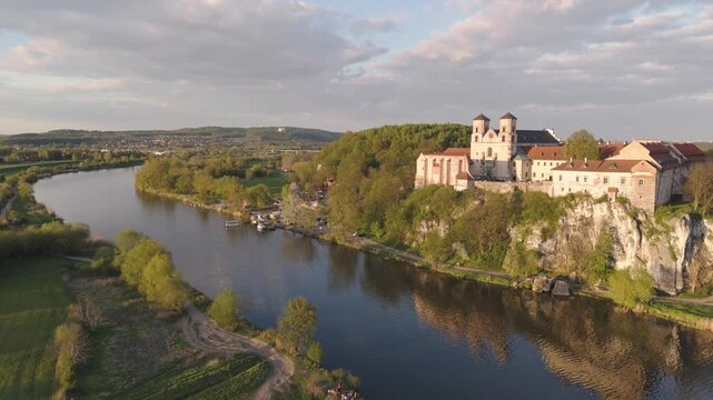 Aerial flyover of an abbey by the river in Poland at sunset in spring