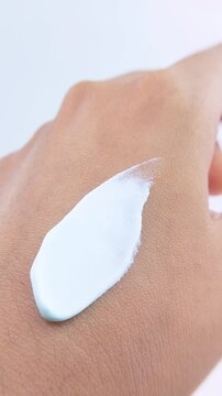 Applying white brightening cream on back of hand. Beauty skincare concept isolated on white background.