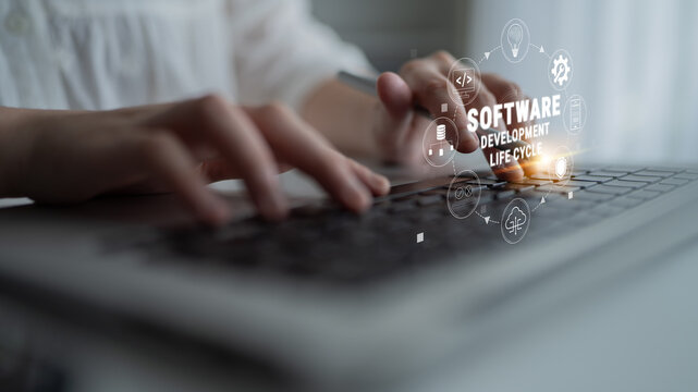 Hands Typing on Laptop Keyboard with Software Development Lifecycle Graphics and Icons Representing Project Phases and Agile Methodologies Quark.