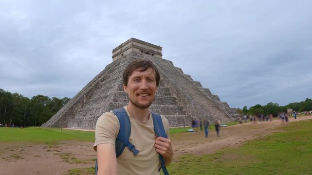 Man traveler is walking in front of Kukulkan pyramid in Chichen Itza, Mexico. Tourist recording a selfie video. Slowmotion shot.