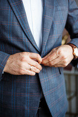 Fototapeta premium Businessman in plaid blazer buttoning suit jacket