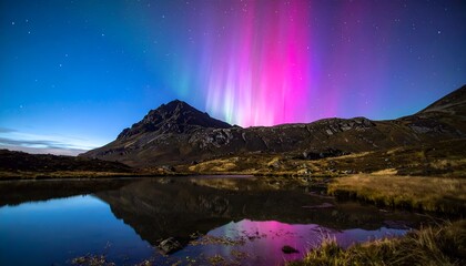 Naklejka premium Colorful aurora borealis reflection in a tranquil lake below mountainous terrain