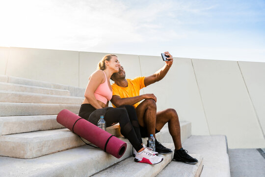 Multiethnic sportive couple training outdoors in the city - Athletic young man and woman doing workout