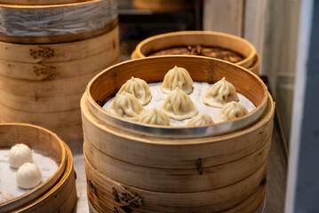 Fototapeta premium Freshly steamed Xiaolongbao (soup dumplings) served in a traditional bamboo steamer at a restaurant in Taiwan.