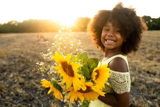 Pretty young african girl in a sunflowers field in bloom 