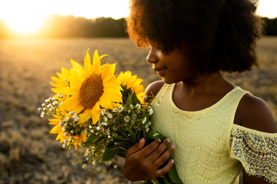 Pretty young african girl in a sunflowers field in bloom 