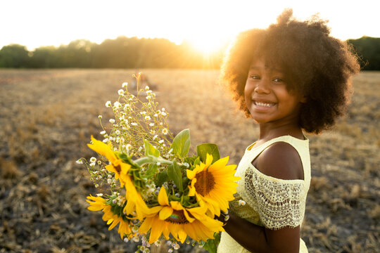 Pretty young african girl in a sunflowers field in bloom 