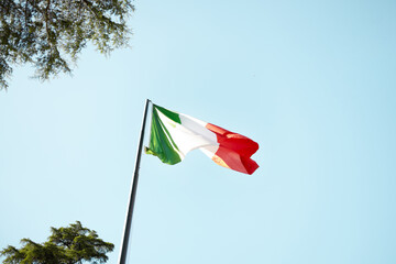 Fototapeta premium National flag of Italy fluttering on flagpole outdoors on a sunny day in Rome.