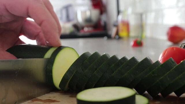 Stockholm, Sweden a cook slices zucchini with a sharp kitchen knife on a wooden board. 