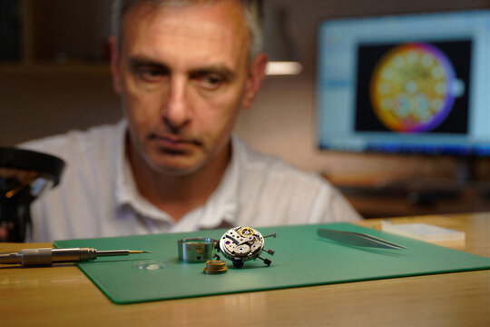 Professional watchmaker working on a mechanical watch movement in his workshop