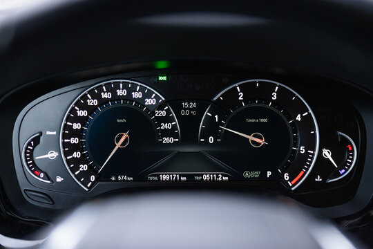 Dashboard display of a modern vehicle showing speedometer and tachometer with digital readouts, illuminated gauges, and various indicators in a sleek black interior