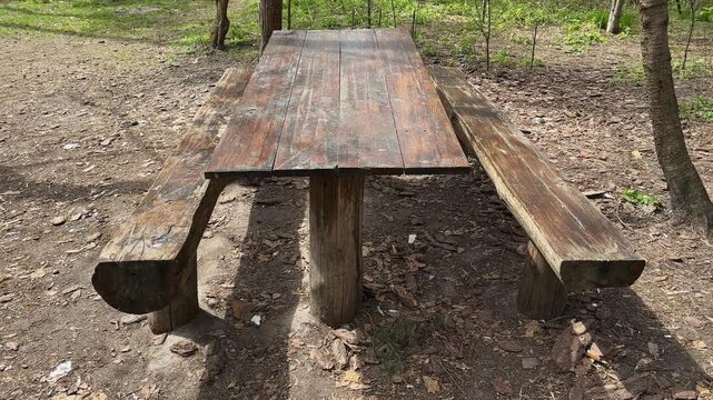 Rough-hewn massive wooden table with benches in a forest