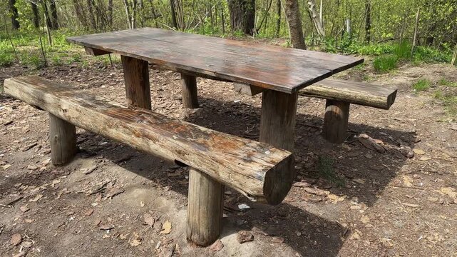 Rough-hewn massive wooden table with benches in a forest