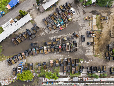 Aerial view of the Animal Market Prambanan with rows of trucks parked on a dirt ground during a busy trading day Kecamatan Prambanan, Jawa Tengah, Indonesia.