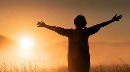 Fototapeta premium The silhouette of a mature woman stands with arms wide open in a vast landscape during golden hour, symbolizing liberation and new beginnings.