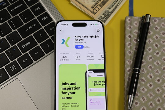 Kiel, Germany - 05-20-2026: Smartphone displaying the XING professional networking and job search app in the App Store in a workspace environment with laptop and notebook