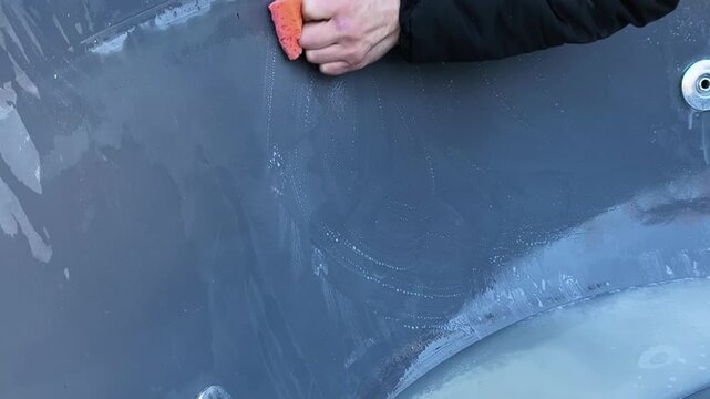 tub cleaning with sponge and water closeup, sanitation concept. Bath surface wet with streaks and drops, tub interior being scrubbed by hand, hygiene routine and maintenance of bathing container