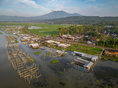 Aerial view of Spot Mancing Sumurup Rawapening featuring traditional fishing platforms and boats on the lake with a mountain backdrop Semarang Regency, Central Java, Indonesia.