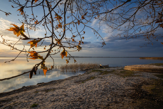 Sunset on the lake. Old rural wooden, fishing boat is moored on the shore of a lake.