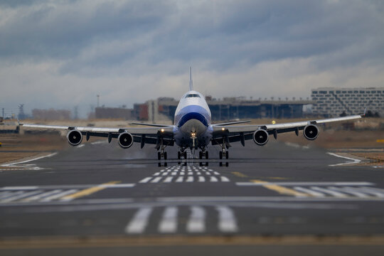 Jumbo jet cargo airplane taxiing head-on down airport runway