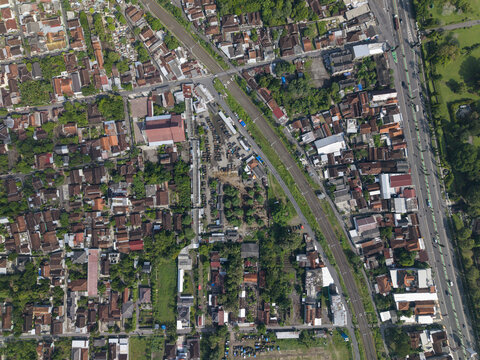 Aerial view of Animal Market Prambanan with dense residential rooftops, narrow streets, and lush green trees in Kecamatan Prambanan, Jawa Tengah, Indonesia.