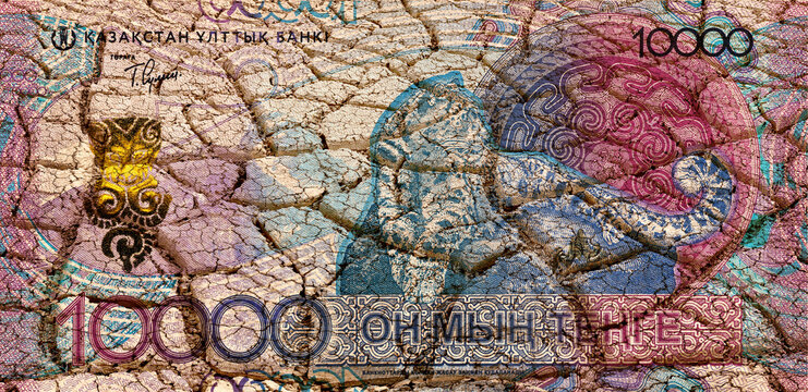 A 10000 Kazakhstan tenge bill against the backdrop of heat-cracked clay in the desert.