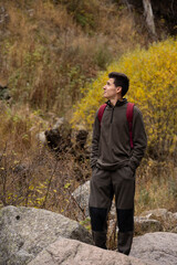 Fototapeta premium A young hiker stands on a rock, admiring the autumn scenery