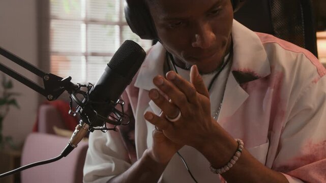 Close up of young adult African American male experimental musician recording hand claps for drum sampling in home production studio equipped with professional microphone