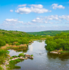 Fototapeta premium small river flow through green canyon under a blue cloudy sky