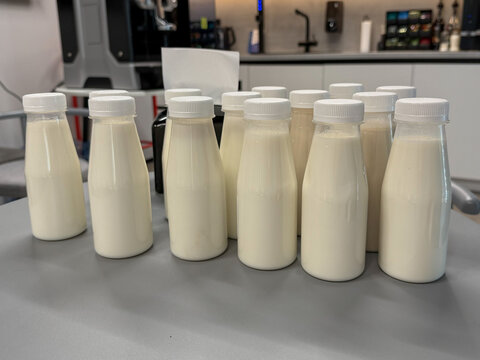 Unlabeled yogurt bottles stand on table for dairy product testing, quality control and food development. Product research, food startup, dairy marketing, packaging test, consumer survey