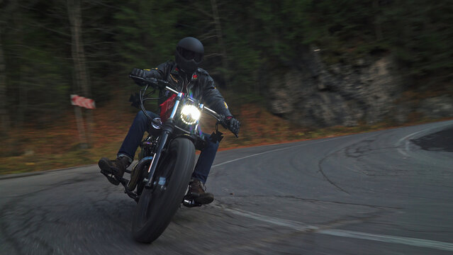 Rider accelerating motorcycle on winding mountain forest road